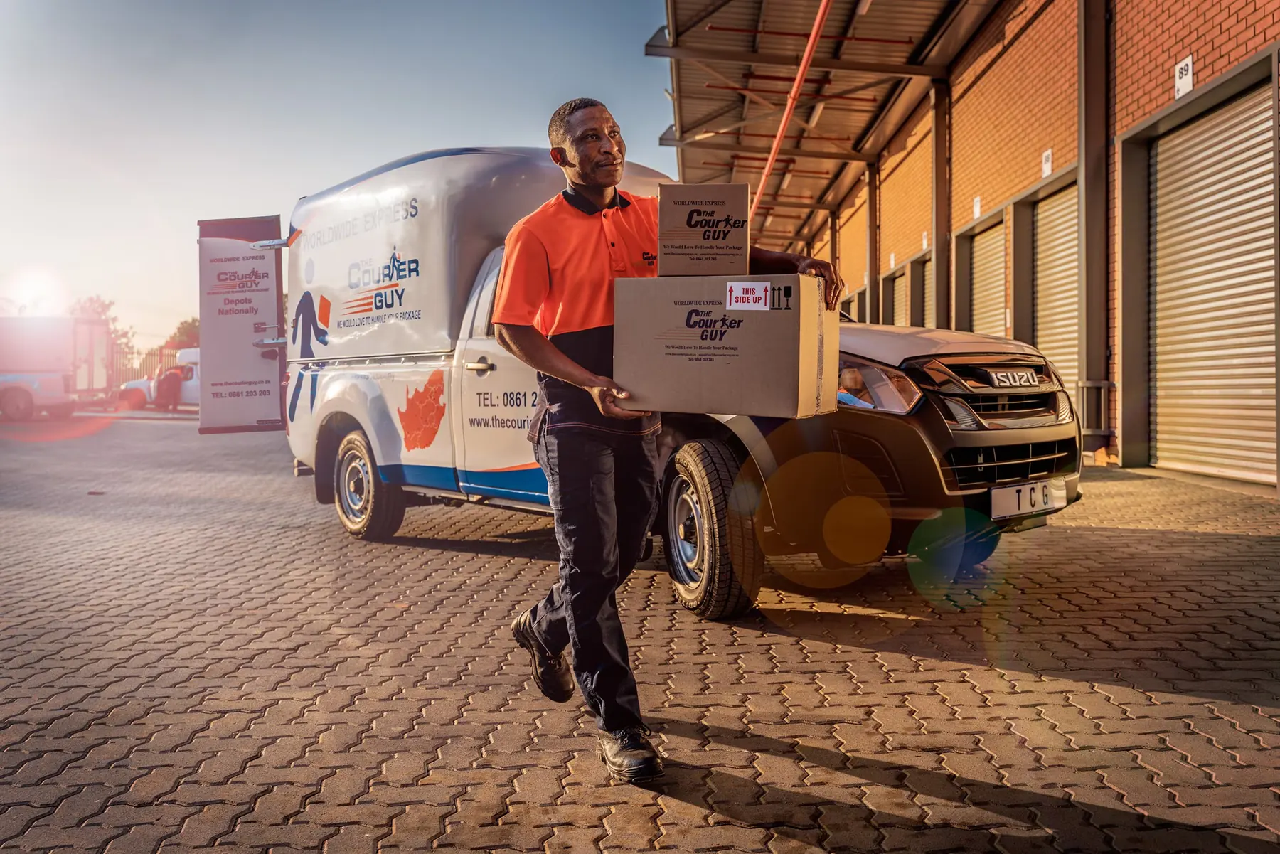 Courier carrying parcels from a delivery bakkie